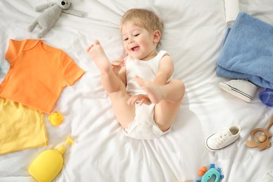 Photo of Cute baby, different clothes and accessories on bed, top view