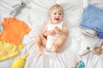 Photo of Cute baby, different clothes and accessories on bed, top view