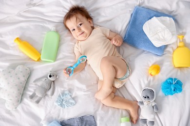 Photo of Cute baby, different clothes and accessories on bed, top view