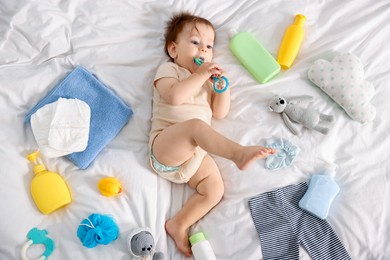 Photo of Cute baby, different clothes and accessories on bed, top view