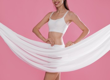 Photo of Woman covering her slim body with silk fabric on pink background, closeup