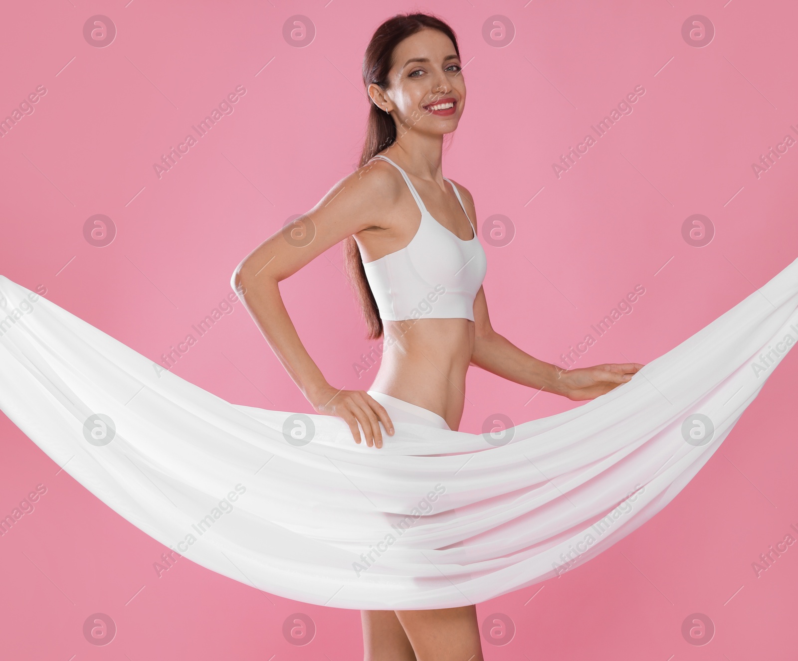 Photo of Woman covering her slim body with silk fabric on pink background