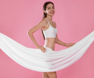 Photo of Woman covering her slim body with silk fabric on pink background