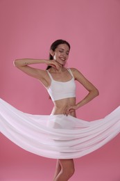 Photo of Woman covering her slim body with silk fabric on pink background