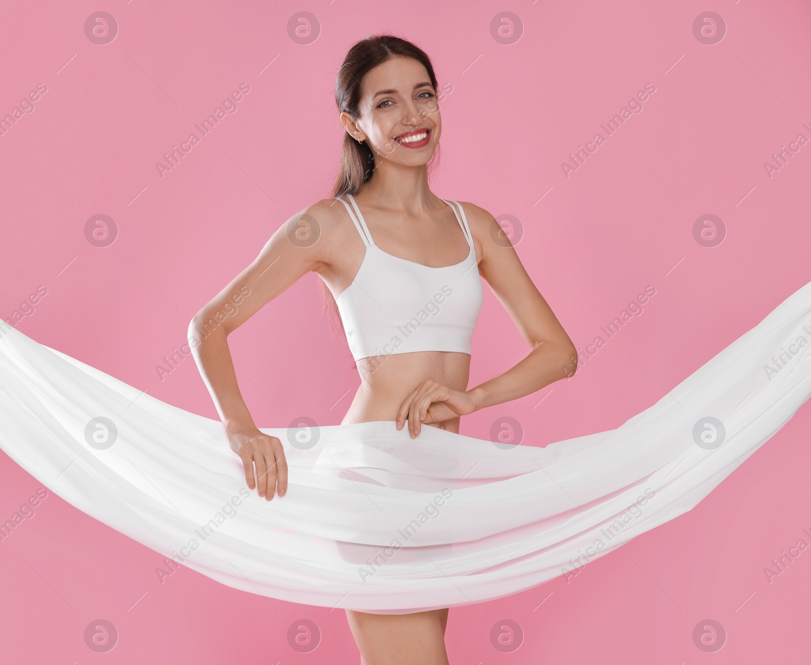 Photo of Woman covering her slim body with silk fabric on pink background
