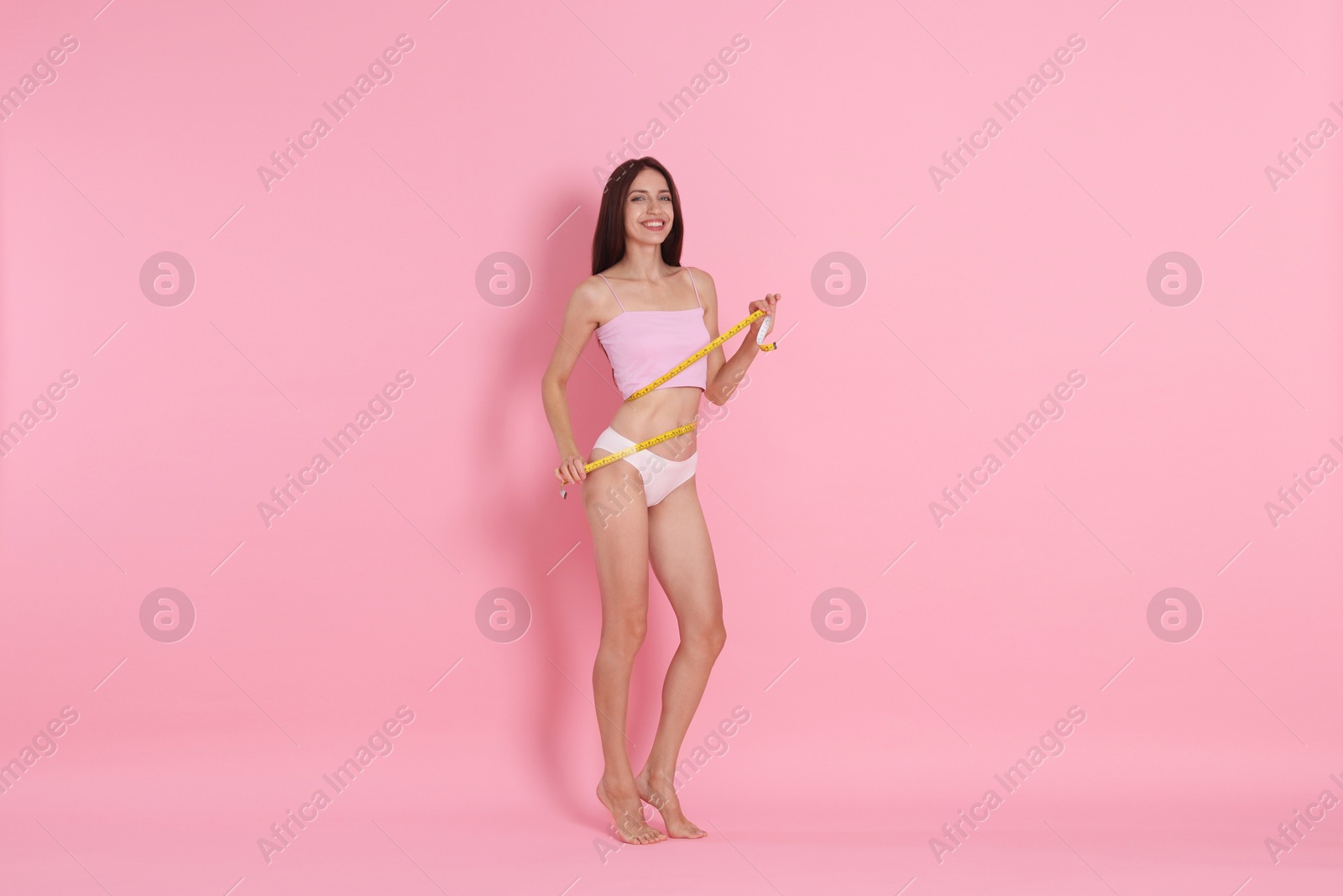 Photo of Woman with slim body and measuring tape on pink background