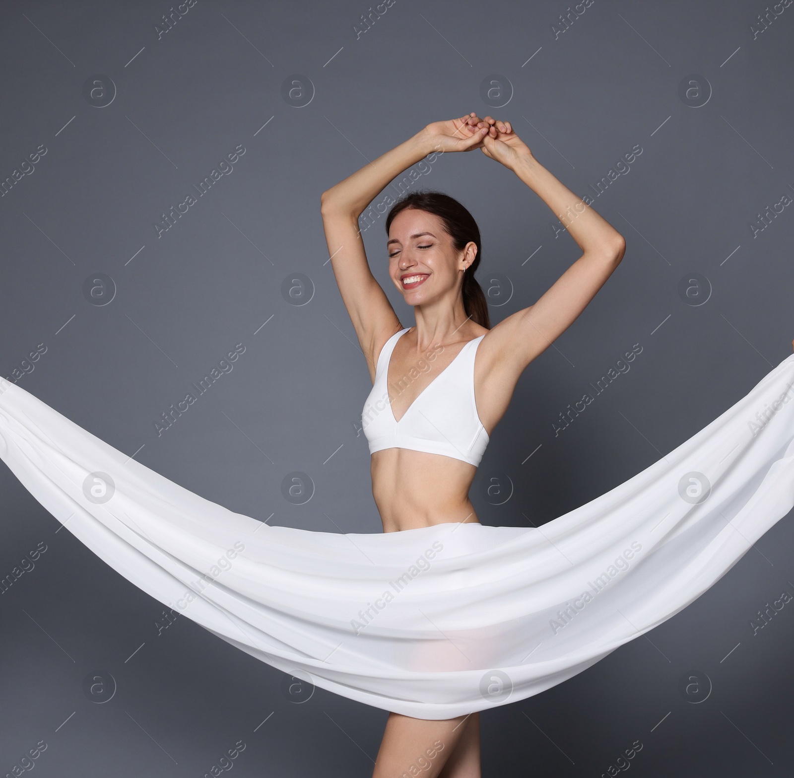 Photo of Woman covering her slim body with silk fabric on grey background