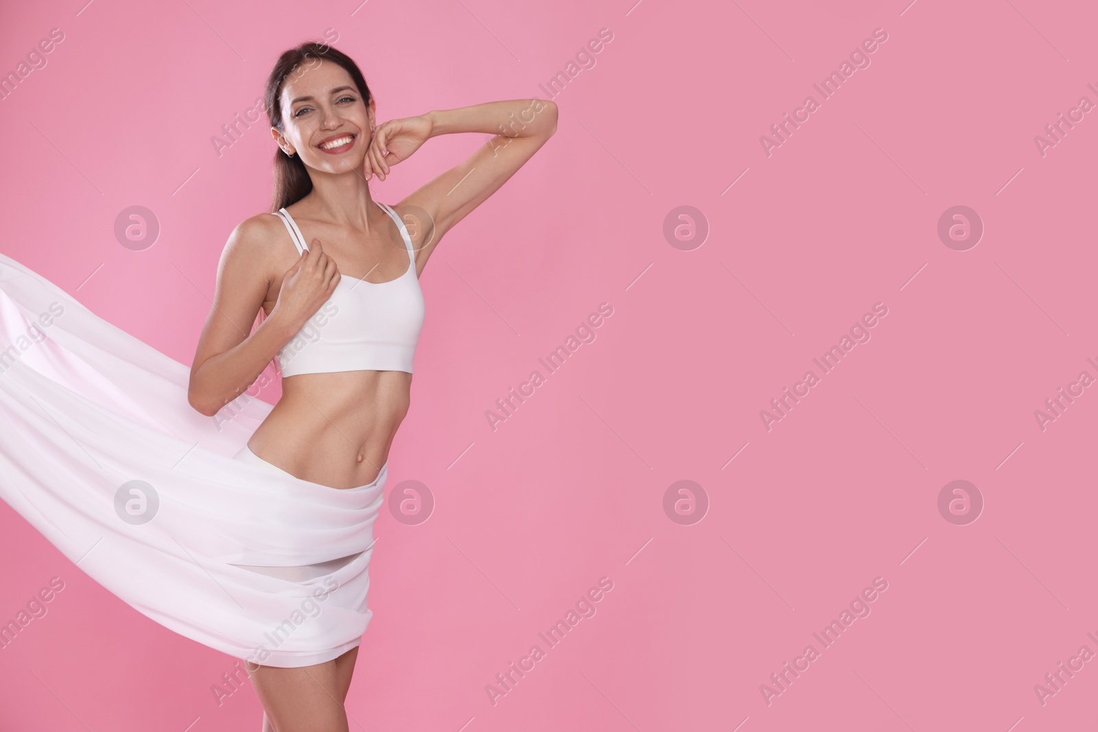 Photo of Woman covering her slim body with silk fabric on pink background, space for text