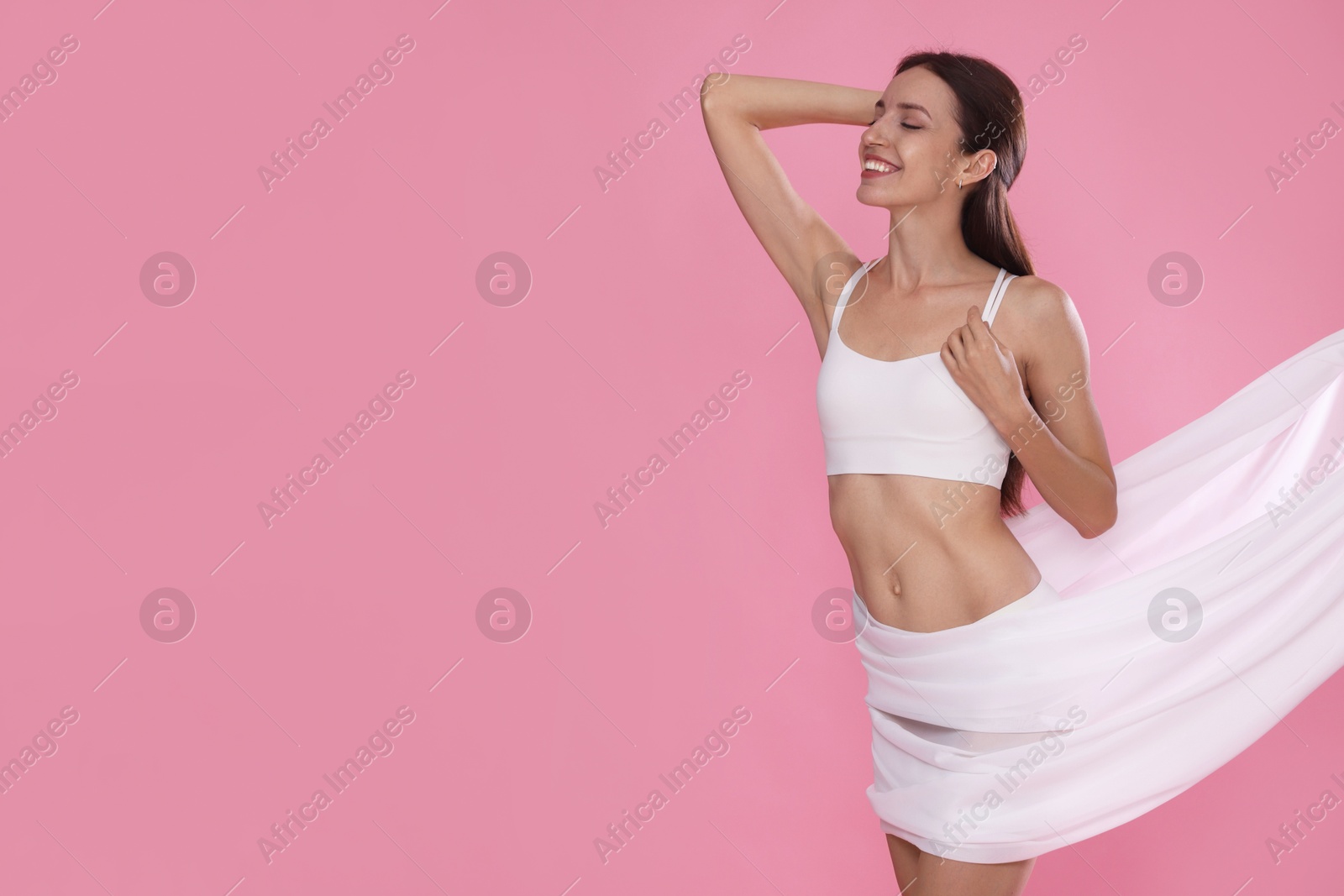 Photo of Woman covering her slim body with silk fabric on pink background, space for text