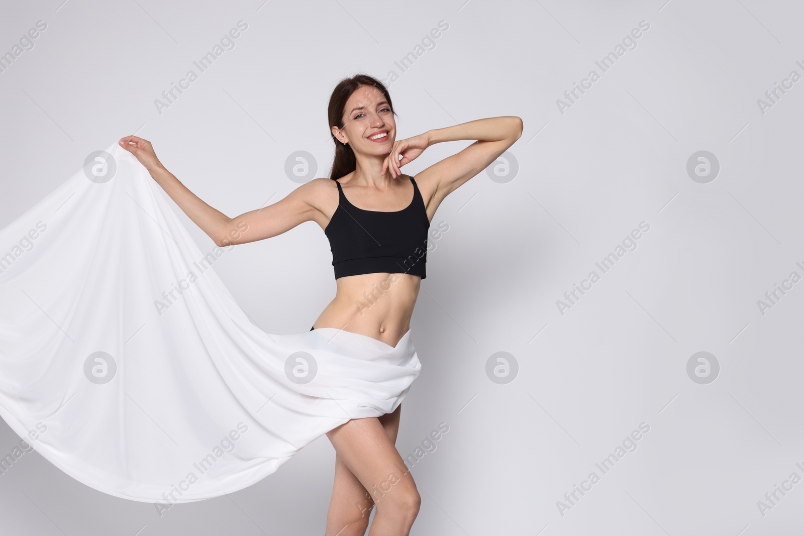 Photo of Woman covering her slim body with silk fabric on white background, space for text