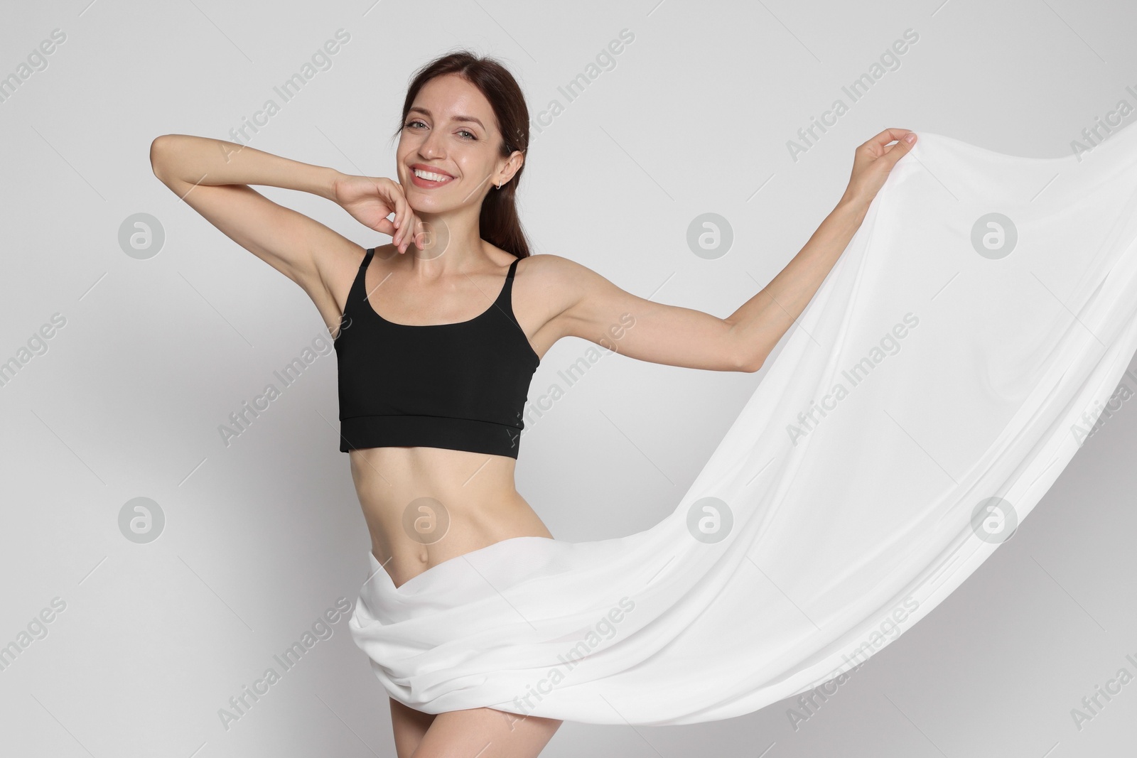 Photo of Woman covering her slim body with silk fabric on white background