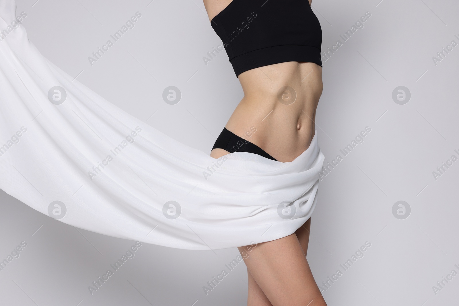 Photo of Woman covering her slim body with silk fabric on white background, closeup