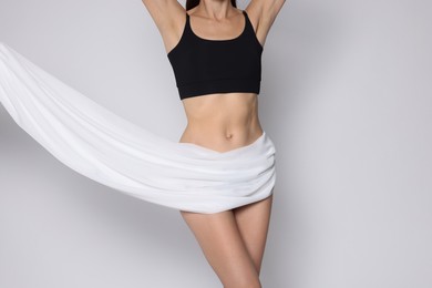 Photo of Woman covering her slim body with silk fabric on white background, closeup