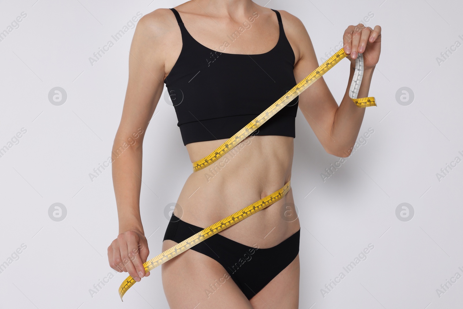 Photo of Woman with slim body measuring waist circumference on white background, closeup