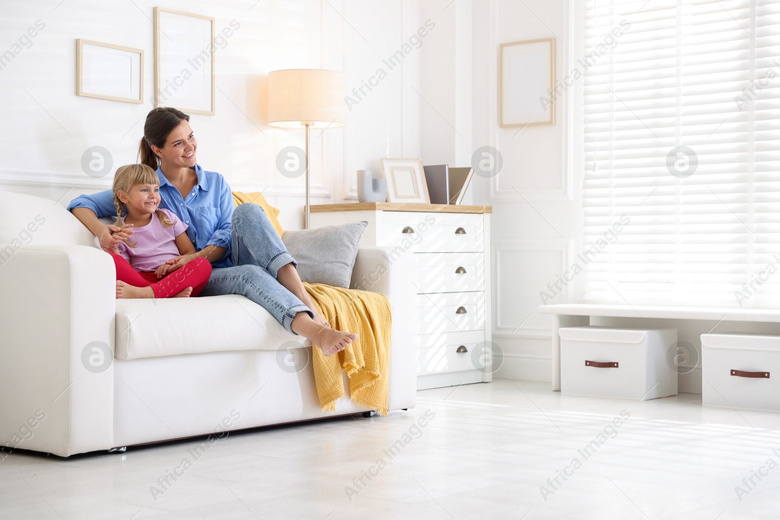 Photo of Happy mother and daughter on sofa at home. Space for text