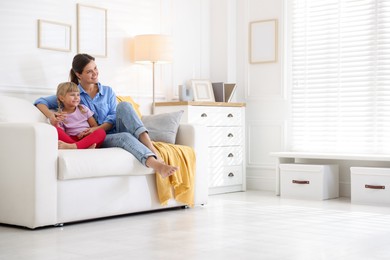 Photo of Happy mother and daughter on sofa at home. Space for text