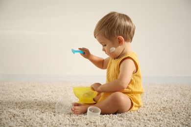 Photo of Cute baby with cream on his body playing at home. Space for text