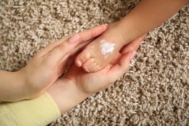 Photo of Mother and baby with cream on his foot at home, closeup