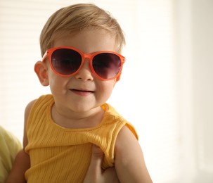 Photo of Mother with her baby wearing sunglasses at home, closeup