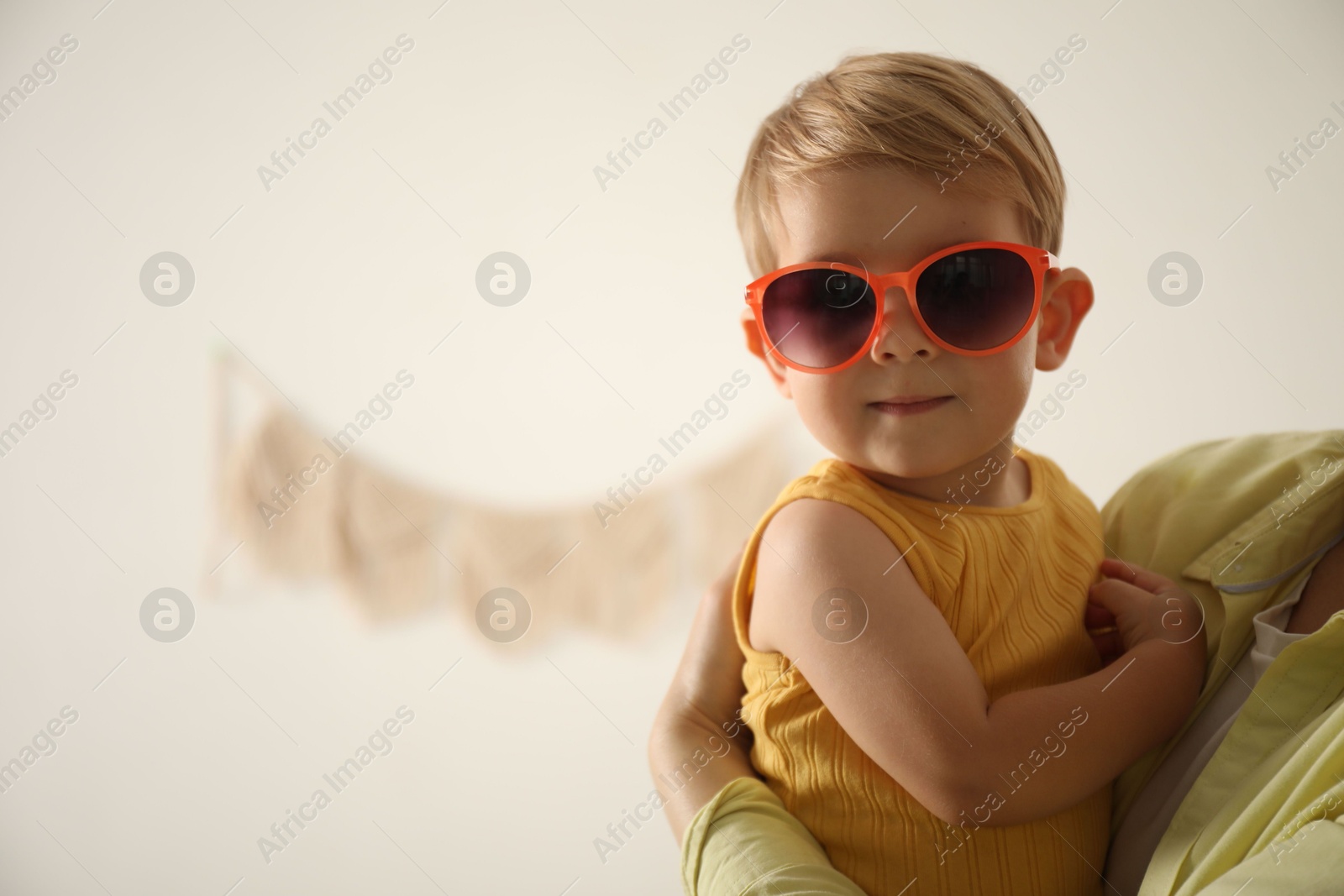 Photo of Mother with her baby wearing sunglasses at home, closeup. Space for text