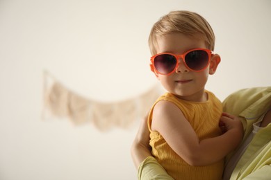 Photo of Mother with her baby wearing sunglasses at home, closeup. Space for text