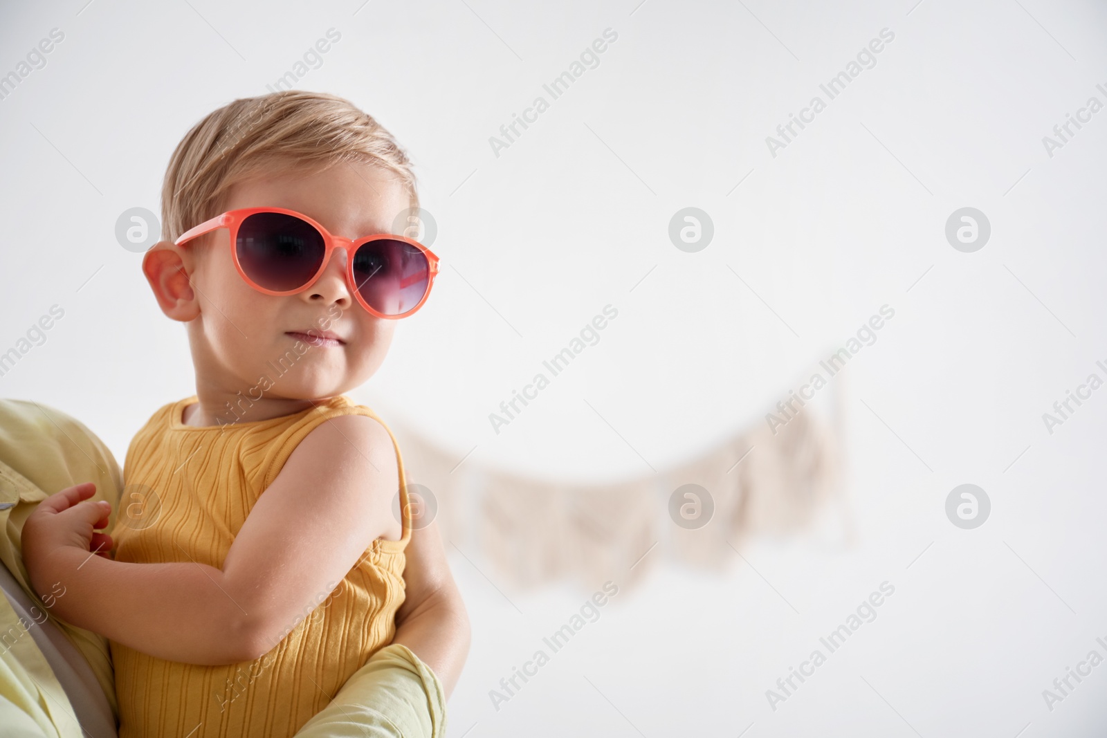 Photo of Mother with her baby wearing sunglasses at home, closeup. Space for text