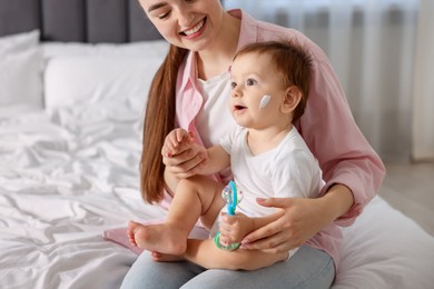 Photo of Mother and baby with cream on his face at home, closeup