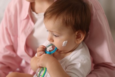 Photo of Mother and baby with cream on his face at home, closeup