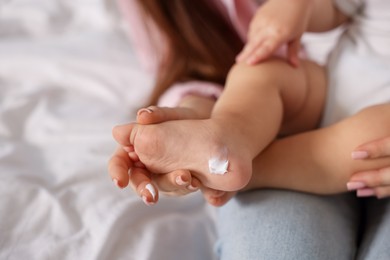 Photo of Mother and baby with cream on his foot at home, closeup