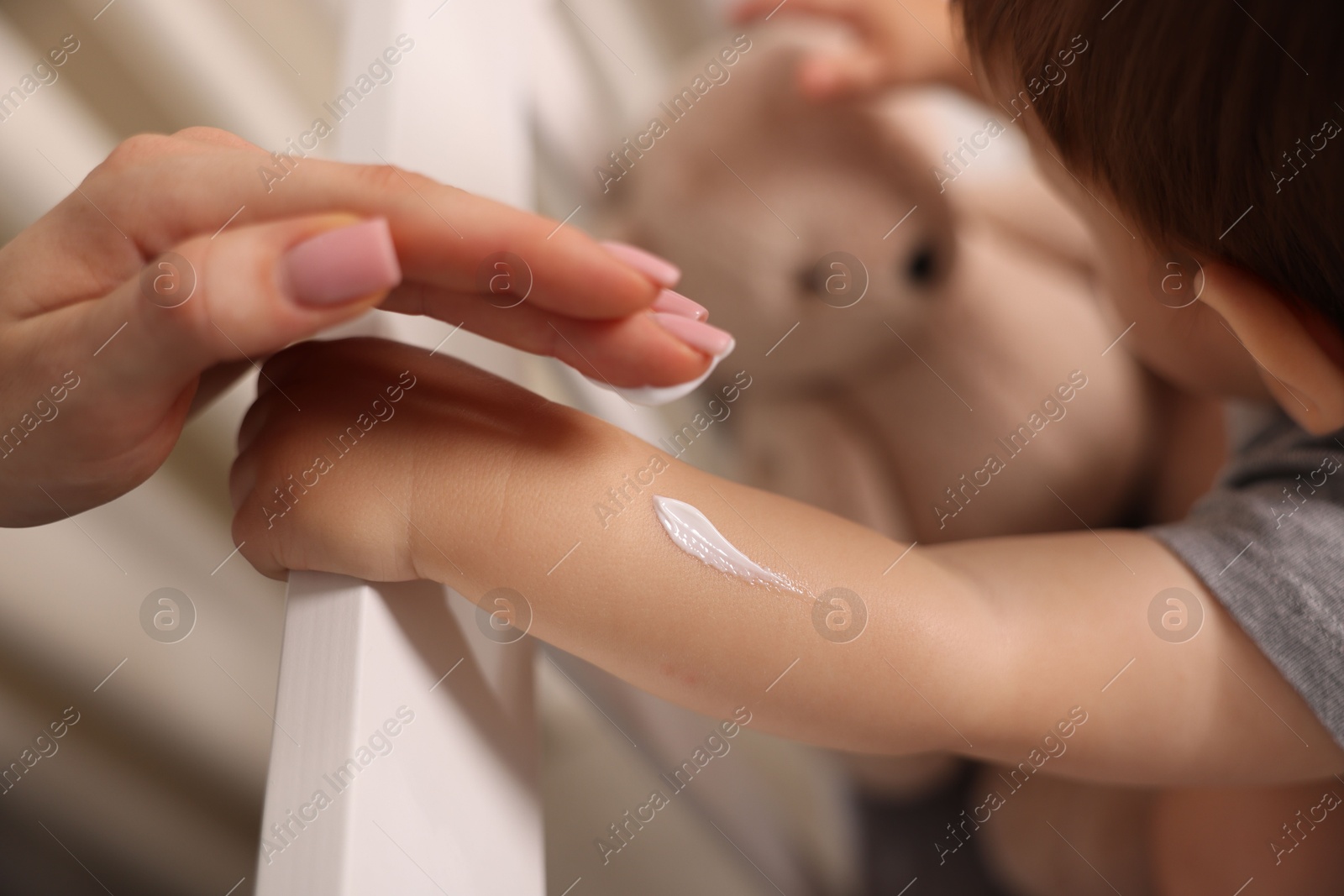 Photo of Mother applying cream onto her baby's arm at home, closeup