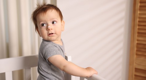 Photo of Baby with cream on his nose in crib at home. Space for text