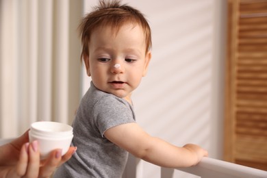 Photo of Mother and baby with cream on his nose at home, closeup