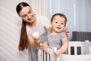 Photo of Mother and baby with cream on his nose at home, selective focus