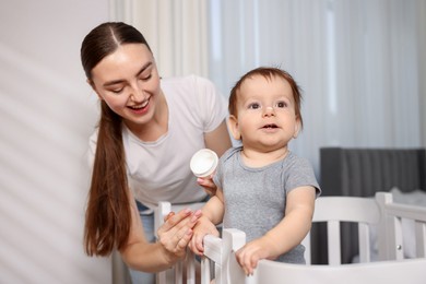 Photo of Mother applying cream onto her baby's arm at home