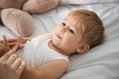 Photo of Mother with her cute baby on bed, closeup