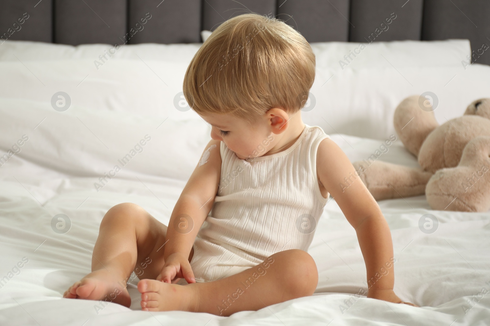 Photo of Cute baby with cream on his arm at home