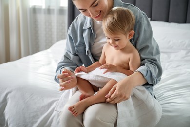Photo of Mother applying cream onto her baby's leg after bath on bed at home, closeup
