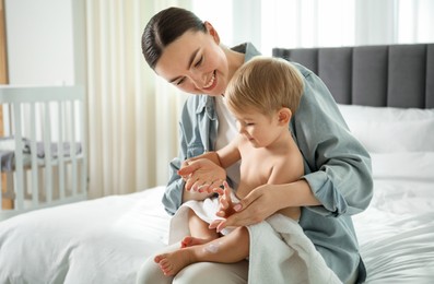 Photo of Mother applying cream onto her baby's body after bath on bed at home