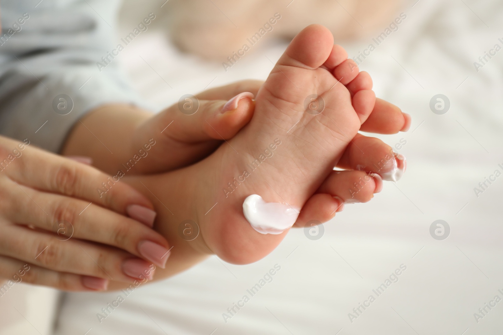 Photo of Mother and her baby with cream on his foot at home, closeup