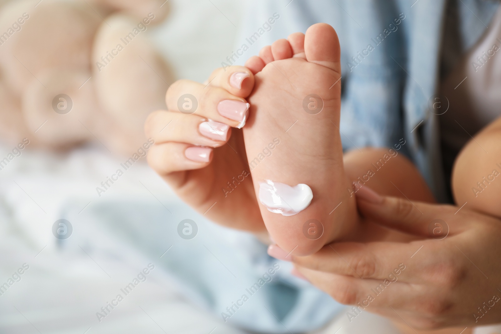 Photo of Mother and her baby with cream on his foot at home, closeup