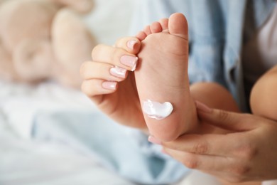 Photo of Mother and her baby with cream on his foot at home, closeup