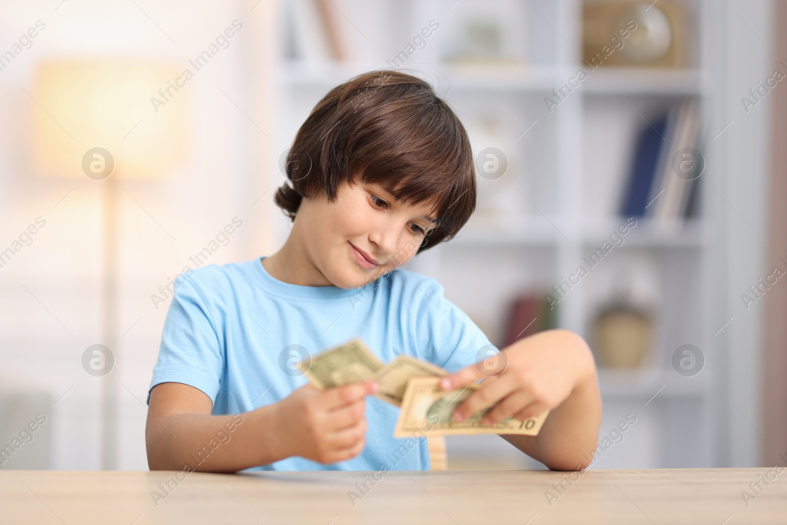 Photo of Boy with pocket money at wooden table indoors
