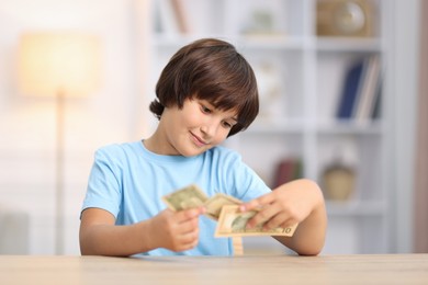 Photo of Boy with pocket money at wooden table indoors