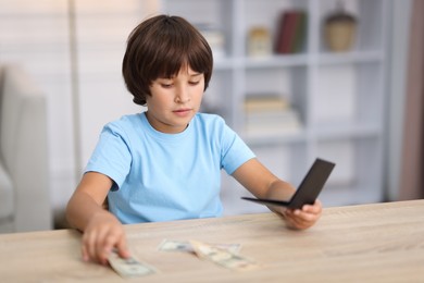Photo of Boy with pocket money at wooden table indoors