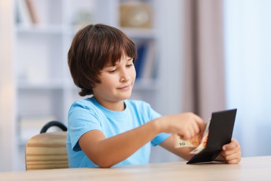 Photo of Boy with pocket money at wooden table indoors