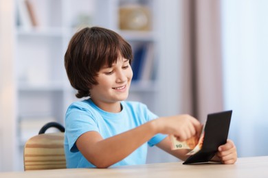 Photo of Boy with pocket money at wooden table indoors