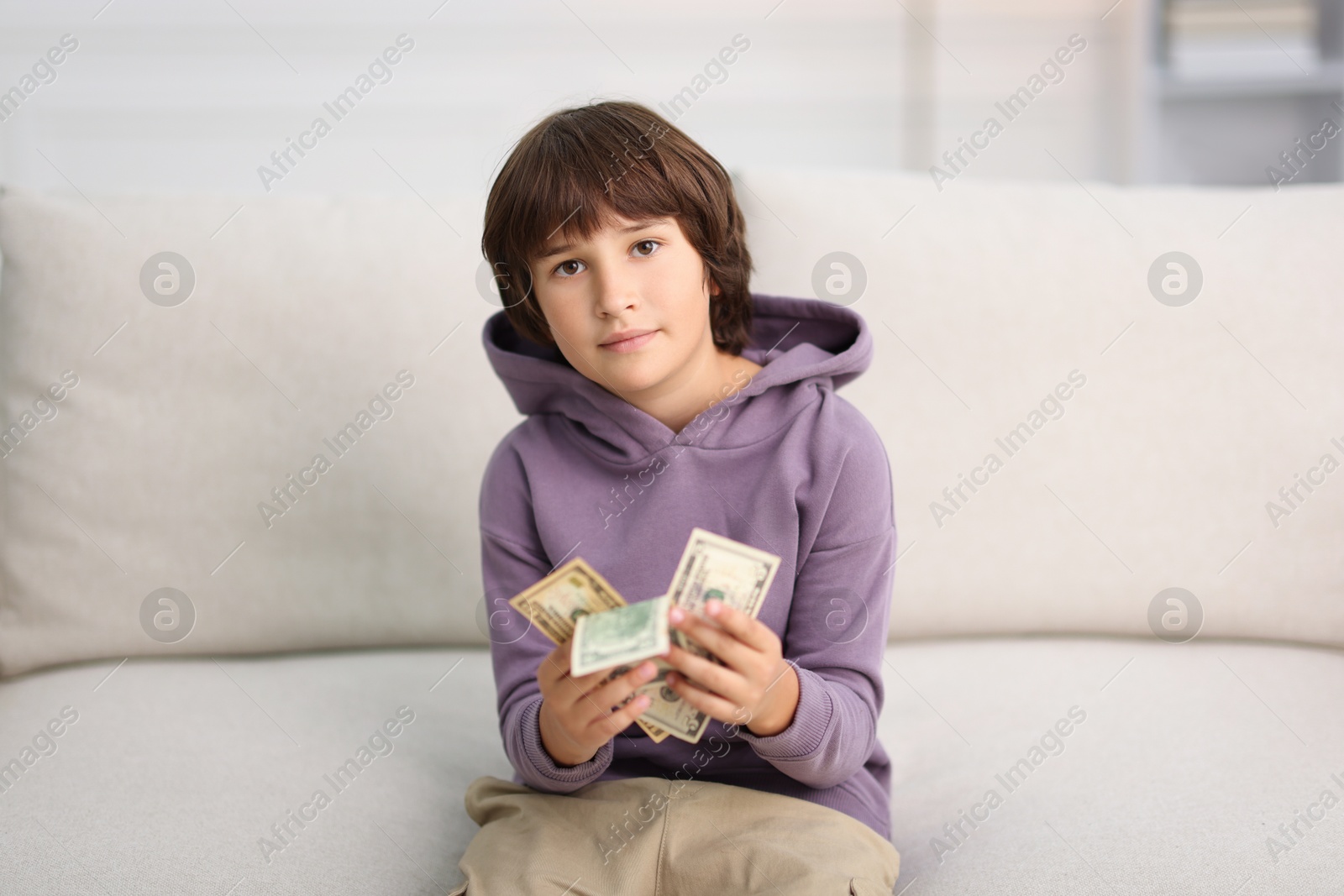 Photo of Boy with pocket money on sofa at home