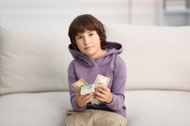 Photo of Boy with pocket money on sofa at home