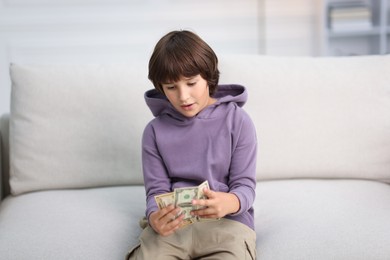 Photo of Boy with pocket money on sofa at home