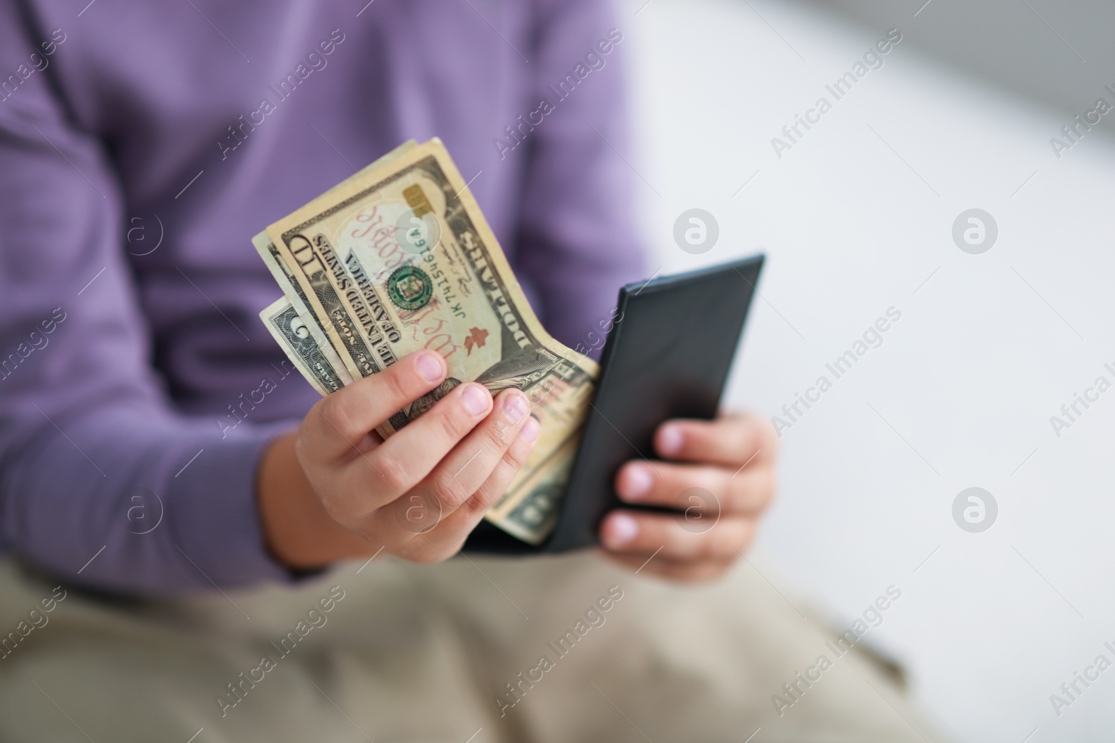 Photo of Boy putting his pocket money into wallet at home, closeup